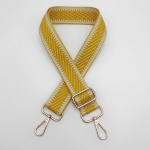 Détail de la bandoulière tissée jaune et blanche avec mousquetons en métal doré