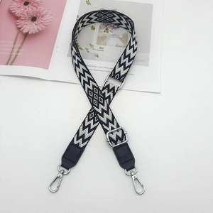 Detail of adjustable black and white geometric canvas bag strap with silver metal hooks