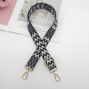 Detail of adjustable black and white geometric embroidered canvas bag strap with gold metal hooks