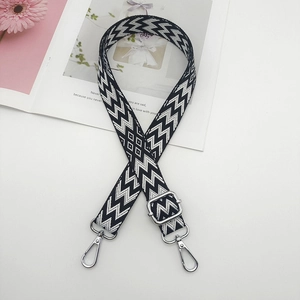 Detail of adjustable black and white geometric canvas bag strap with silver metal swivel hooks