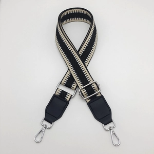 Detail of adjustable black and white geometric canvas bag strap with silver metal hooks