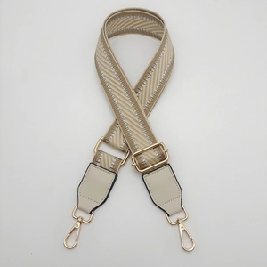 Detail of adjustable woven canvas strap with silver metallic thread and gold swivel hooks