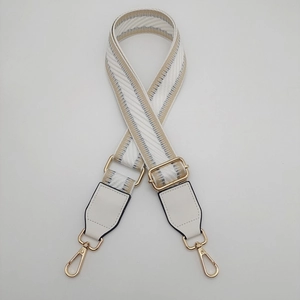 Detail of adjustable white and gold geometric woven strap with golden swivel snap hooks