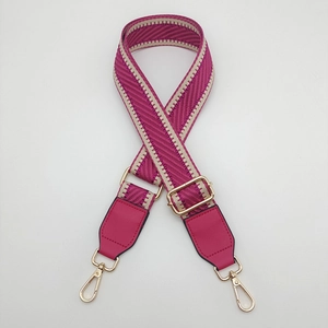 Detail of adjustable chevron woven canvas bag strap with gold metal hooks and leather trim