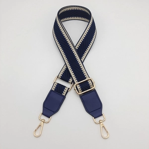 Detail of adjustable geometric navy blue and beige woven strap with gold metal hooks