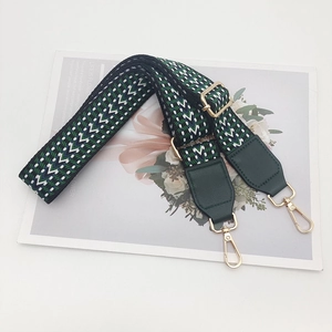 Detail of adjustable geometric nylon strap with gold metal hooks and green leather ends
