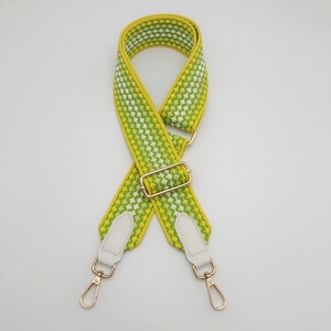Detail of adjustable geometric woven bag strap with white PU leather and gold metal hooks