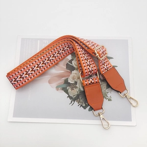 Detail of adjustable geometric jacquard strap with orange leather and gold metal hooks