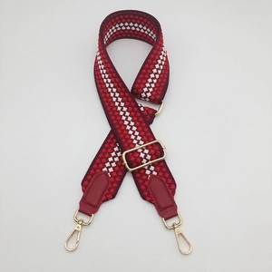 Detail of red and white geometric woven strap with gold metal buckles and leather ends