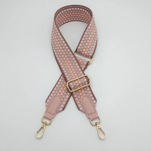 Detail of adjustable geometric wave pattern woven bag strap with golden lobster clasps