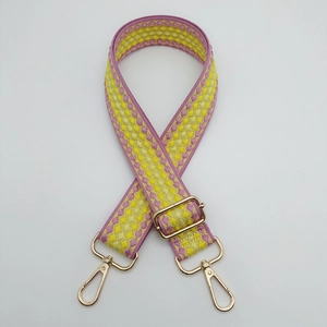 Detail of adjustable woven shoulder strap with pink and yellow plaid pattern and gold hooks