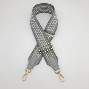 Detail of grey honeycomb woven bag strap with adjustable gold buckle and leather ends