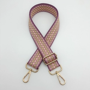 Close-up of woven bag strap with purple geometric patterns and gold metal swivel hooks
