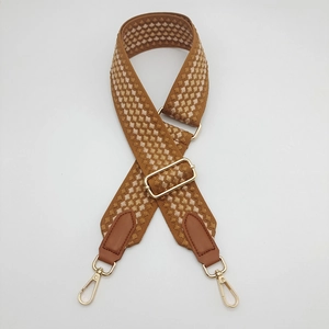 Detail of adjustable brown geometric woven strap with gold lobster clasps and PU leather