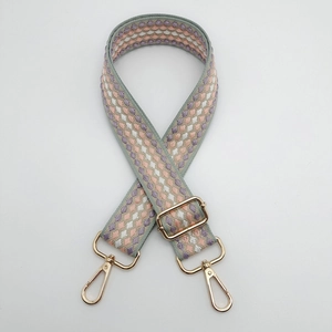 Detail of adjustable geometric woven bag strap with golden metal lobster clasps