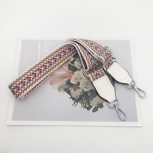 Detail of colorful geometric woven bag strap with silver metal hooks and white leather ends