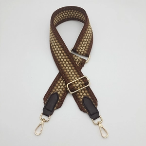Macro view of adjustable woven 5cm shoulder strap with golden metal lobster clasps