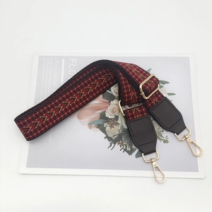 Detail view of woven ethnic style strap with gold metal hooks and dark brown leather
