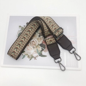 Detail of bohemian weave strap with brown leather ends and dark grey metal hooks