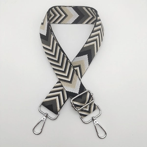 Macro detail of adjustable chevron pattern woven bag strap with silver metal swivel hooks