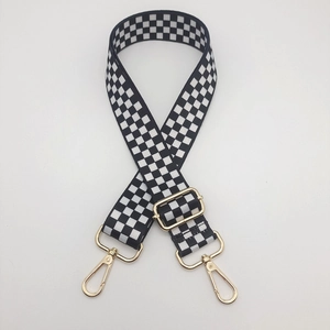 Detail view of black and white checkered replacement bag strap with gold metal hardware