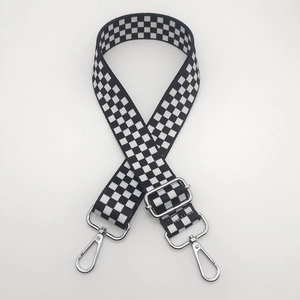 Close-up of black and white checkerboard woven bag strap with silver metal swivel hooks