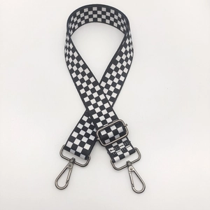 Detail view of black and white checkerboard nylon strap with gunmetal buckles