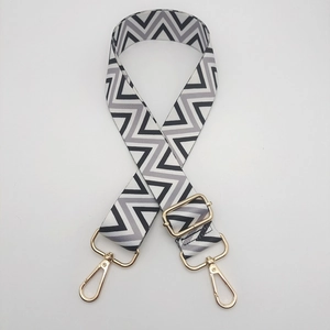 Detail of adjustable nylon strap with black and white wave pattern and gold metal hooks