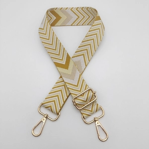 Detail of adjustable wide shoulder strap with yellow chevron weave and gold metal hooks