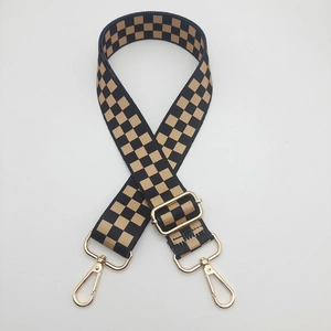Detail of adjustable wide nylon bag strap with brown checkerboard pattern and gold clips