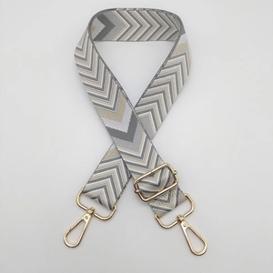 Detail of adjustable geometric weave bag strap with gold lobster clasps and grey waves