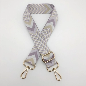 Detail of adjustable thick woven bag strap with purple wave pattern and gold metal hooks