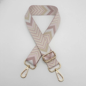 Detail of adjustable chevron woven strap with pink and beige patterns and gold hardware