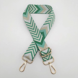 Detail of adjustable green and beige woven shoulder strap with gold metal buckles
