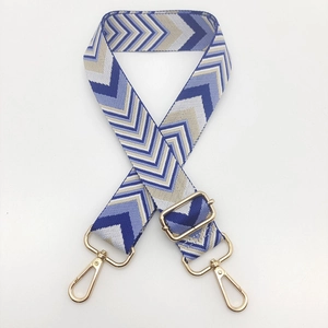 Macro detail of the woven chevron pattern and gold metal lobster clasps on the bag strap
