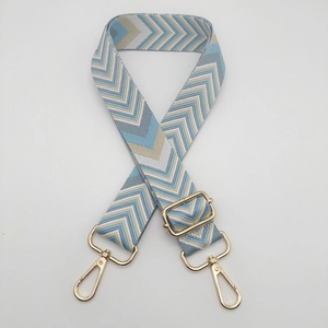 Close-up of thick adjustable strap with geometric wave pattern and gold metal hooks