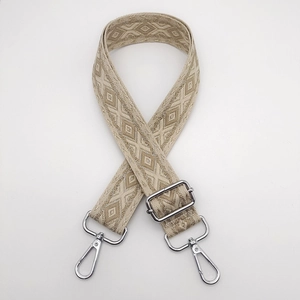 Close-up of wide ethnic woven strap with beige diamond patterns and silver metal hooks