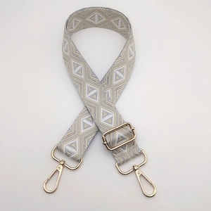 Detail of adjustable geometric ethnic strap with light gold metal swivel hooks and buckles