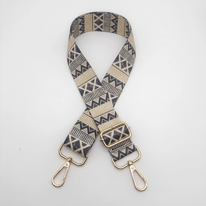 Close-up of ethnic geometric pattern nylon strap with polished gold-tone metal hardware