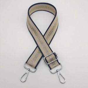 Detail of adjustable woven bag strap with classic stripes and silver metal hooks