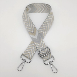 Detail of adjustable wide woven bag strap with silver metal hooks and chevron pattern
