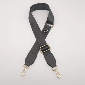 Close-up of adjustable dark gray nylon shoulder strap with gold lobster clasps and D-ring