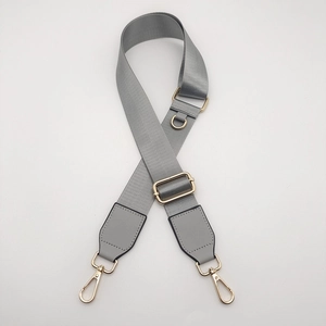 Close-up of grey nylon bag strap with gold metal D-ring and rotating lobster clasps