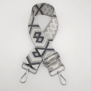 Detail of gray geometric nylon bag strap with silver metal lobster clasps and buckle