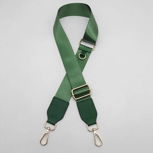 Detail of adjustable green nylon bag strap with gold metal hooks and leather patch