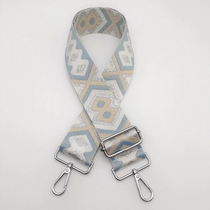 Detail of blue and beige ethnic patterned nylon bag strap with silver metal hardware