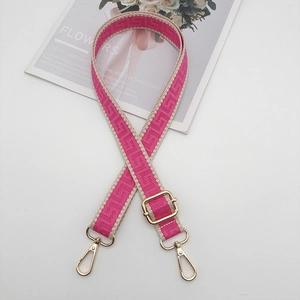 Detail of adjustable wide jacquard strap with gold metal hooks for handbags