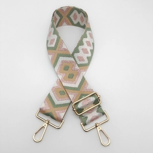 Detail of retro geometric woven bag strap with golden lobster clasp and adjustable buckle