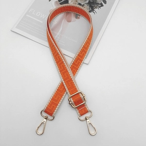 Close-up of orange geometric patterned bag strap with golden metal lobster clasps