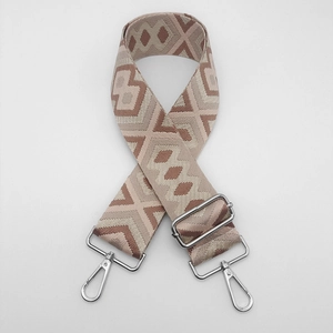 Close-up of geometric jacquard bag strap with silver swivel hooks and adjustable buckle